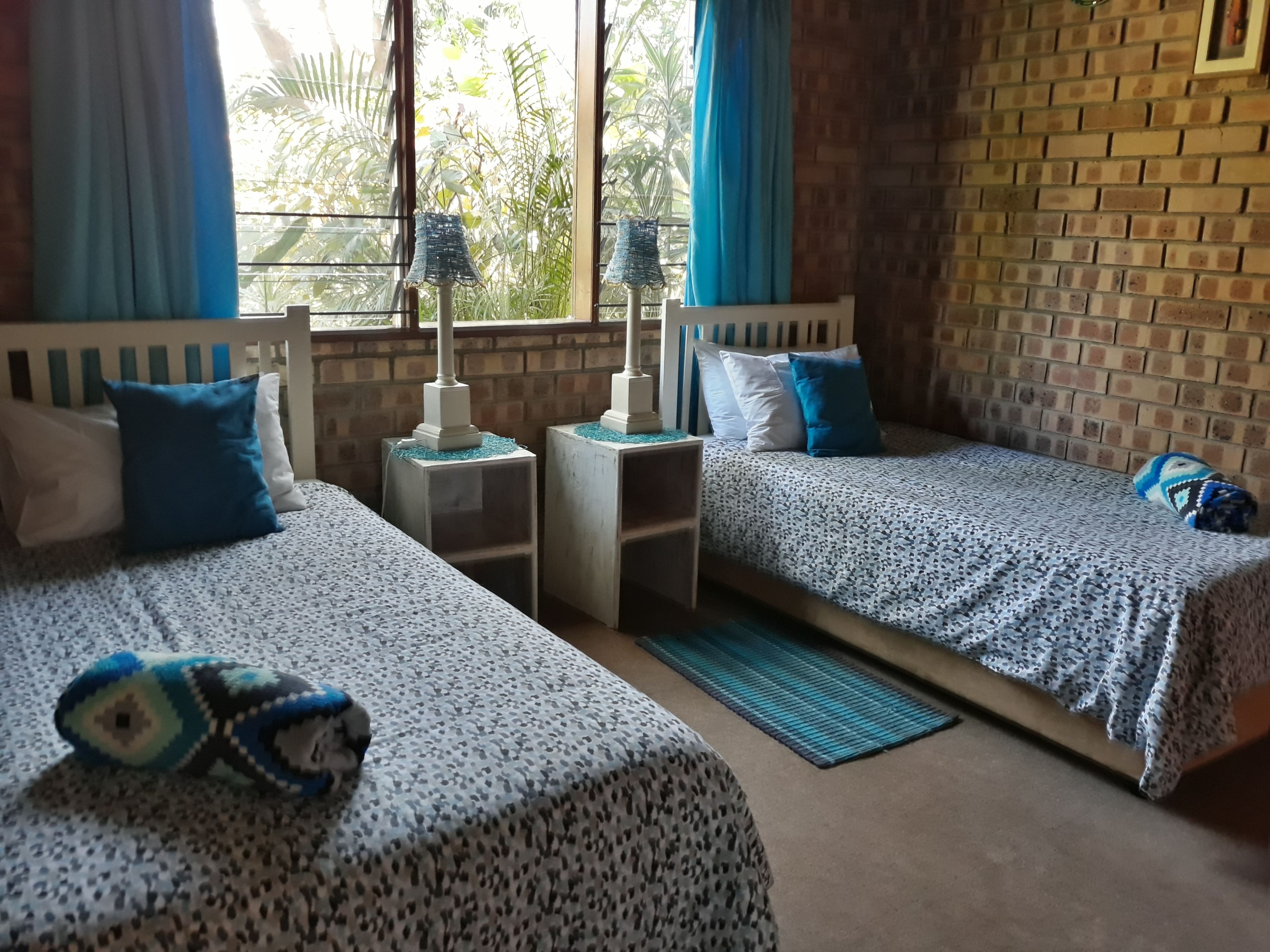 Una habitación con dos camas, una mesita y una ventana con cortinas.