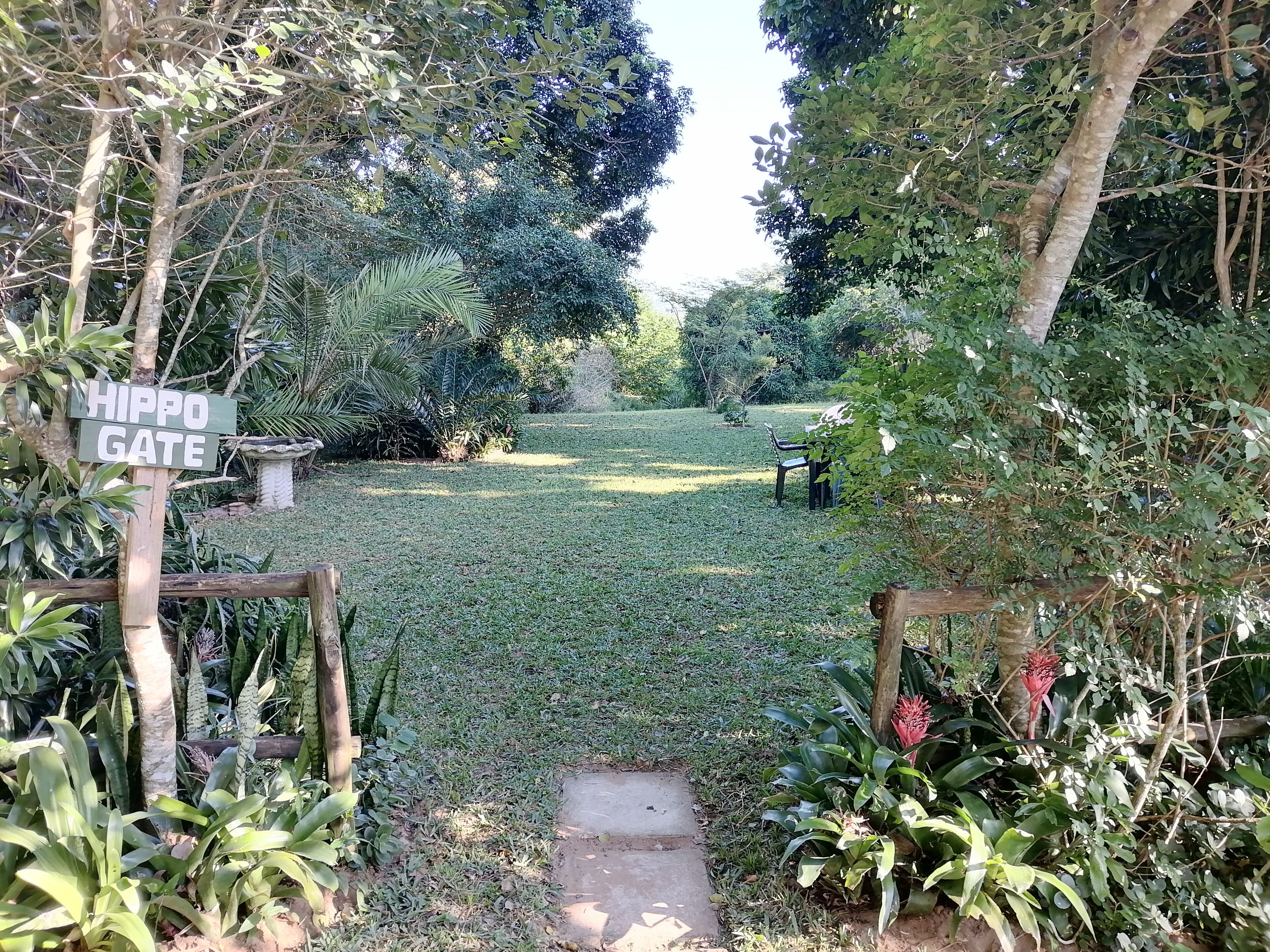 A garden with a sign reading "HIPPO GATE," a pathway, and various plants.