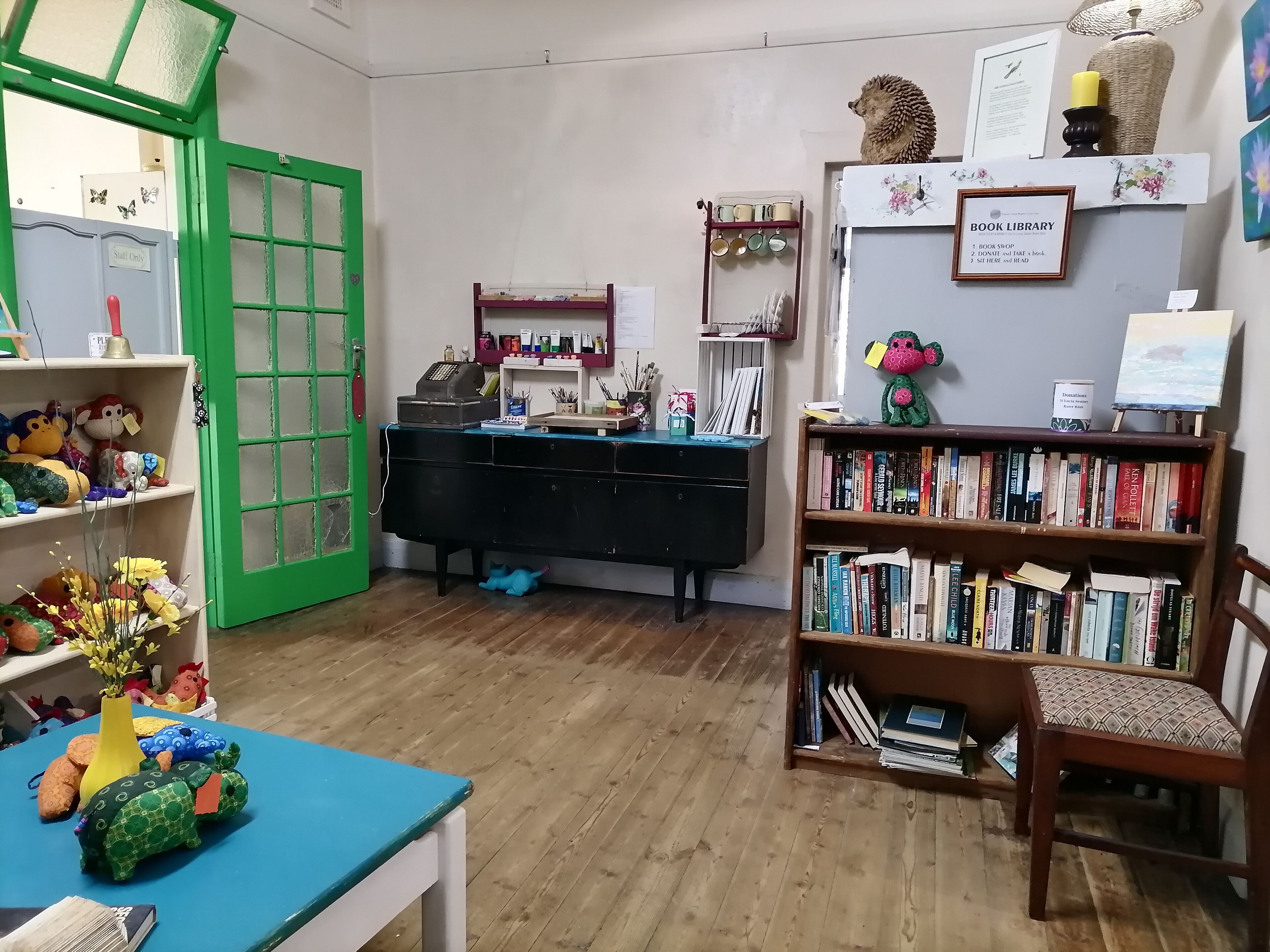 A cozy room with a green door, a desk with a computer, a bookshelf, and a small table with toys.