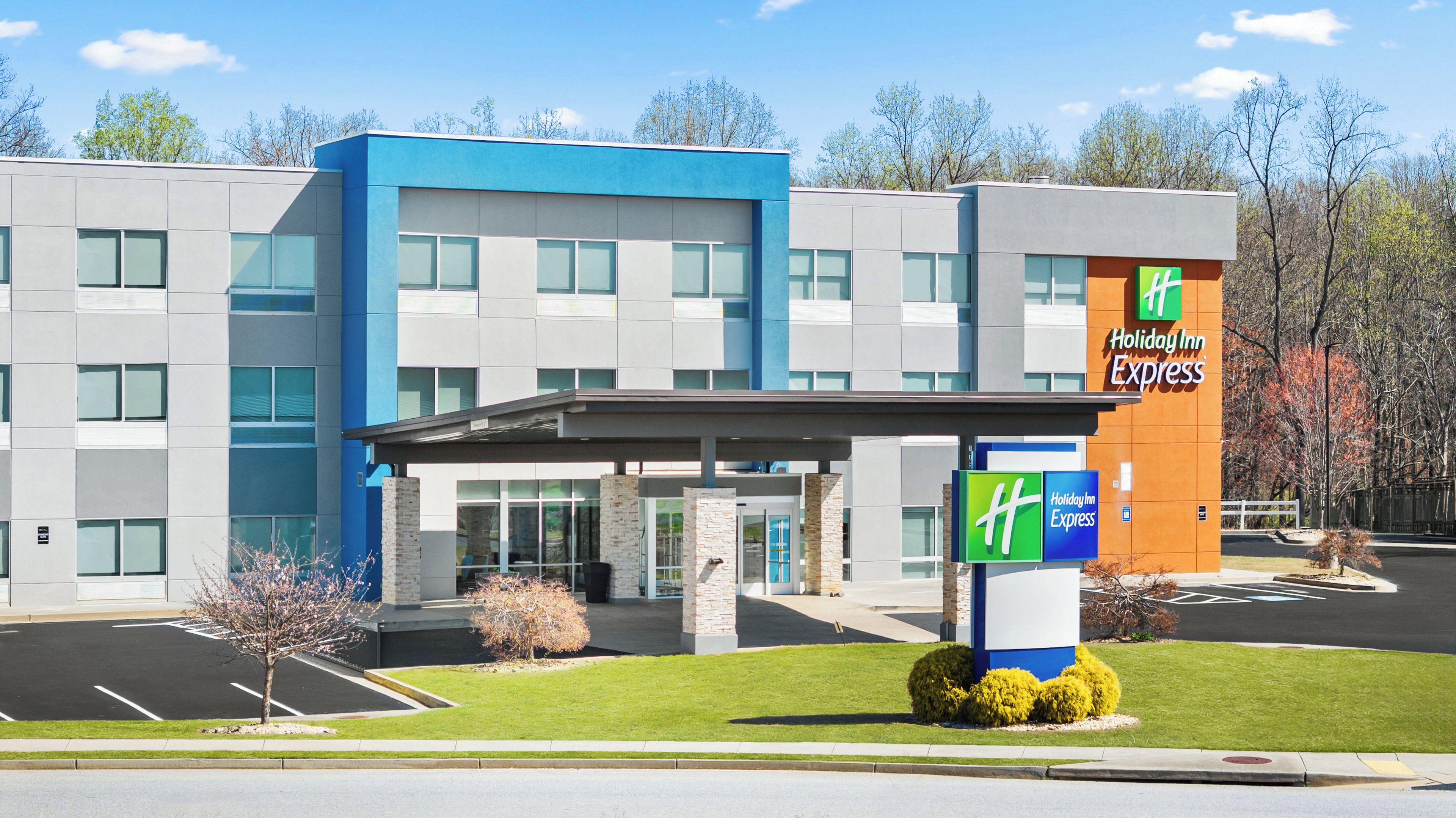 A Holiday Inn Express hotel with a modern design, featuring a large entrance and a parking lot.