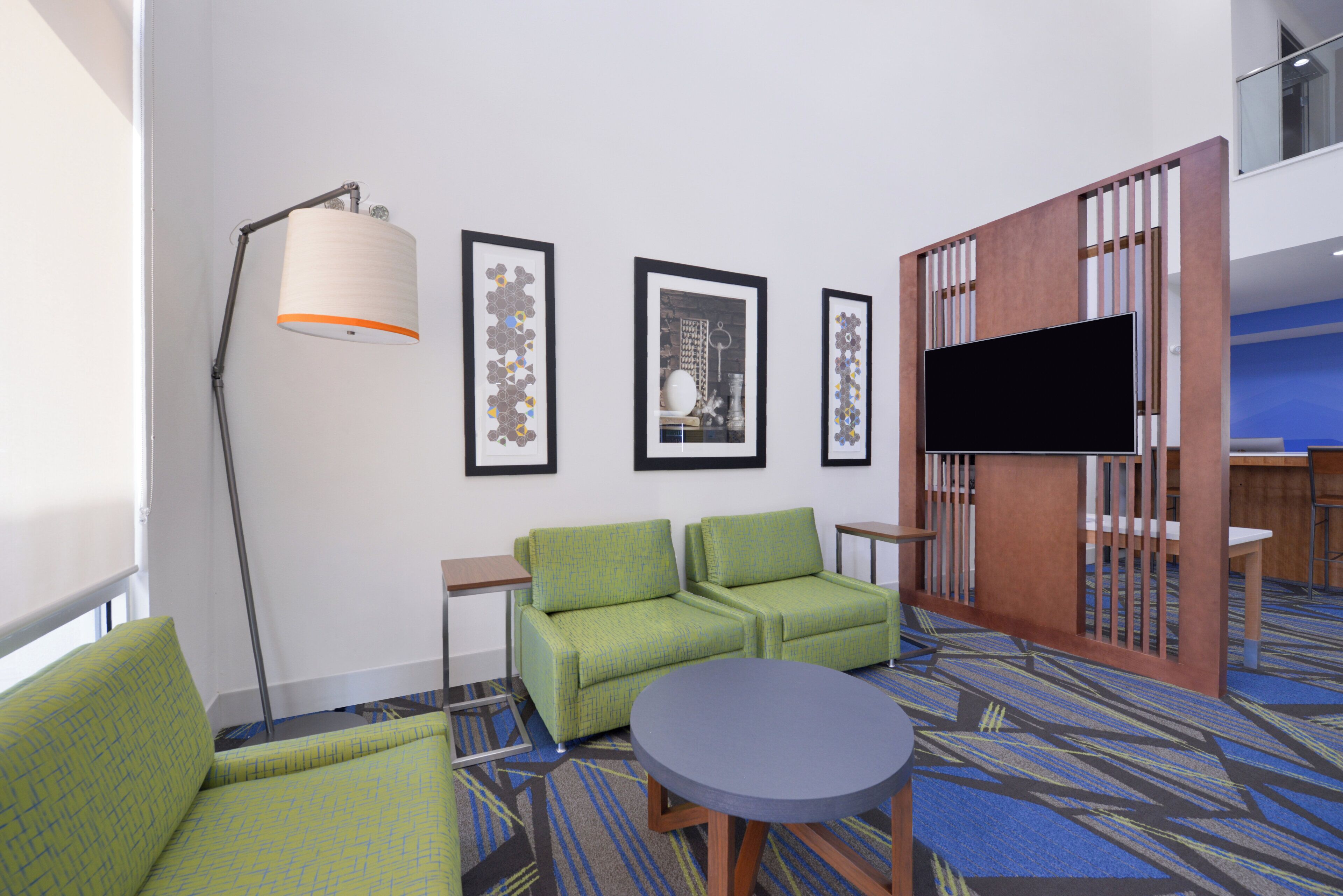 Habitación de hotel con sofá, una mesa redonda, televisión y cuadros en la pared.