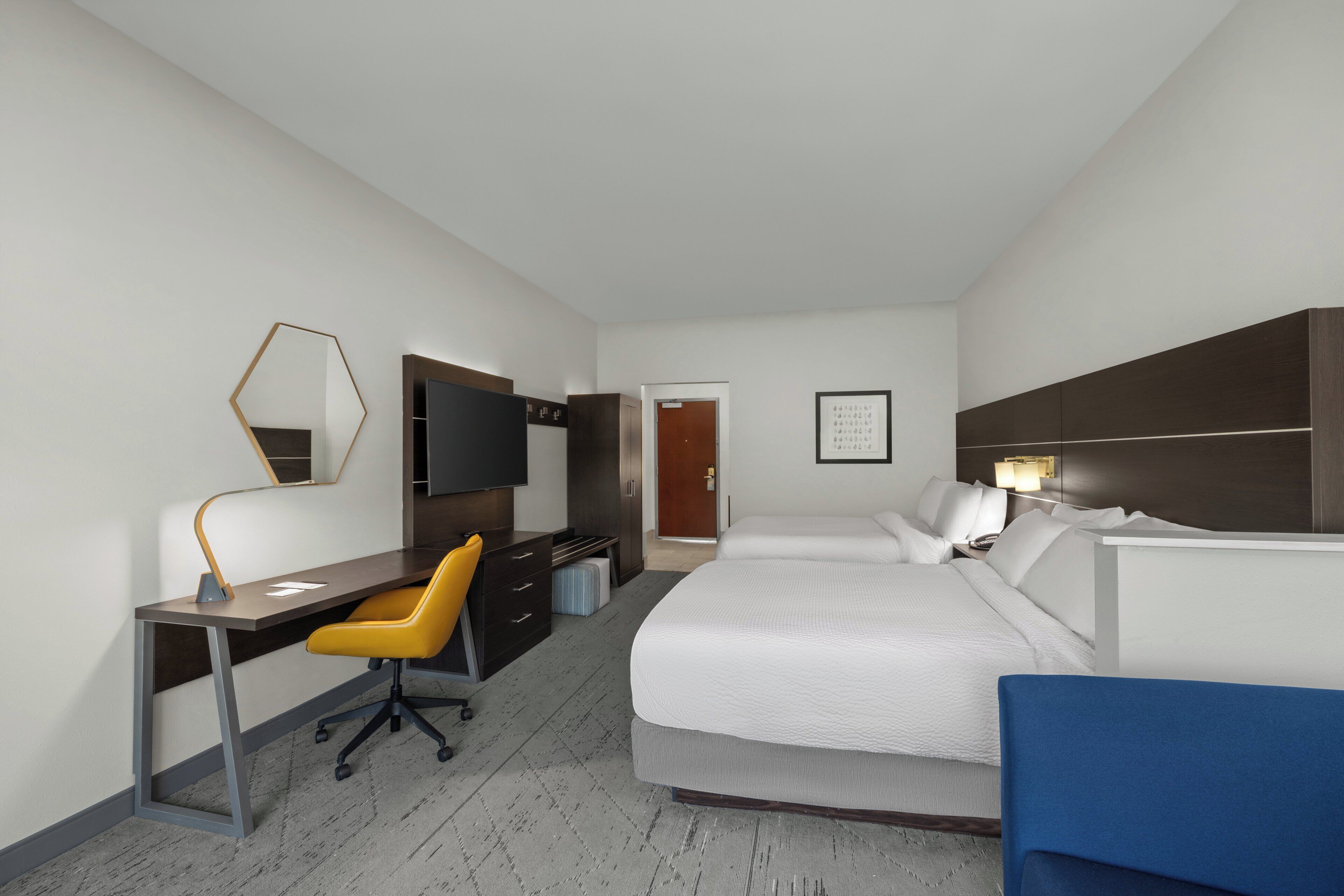 Ein Hotelzimmer mit Bett, Schreibtisch, Stuhl, Fernseher und einer Tür.