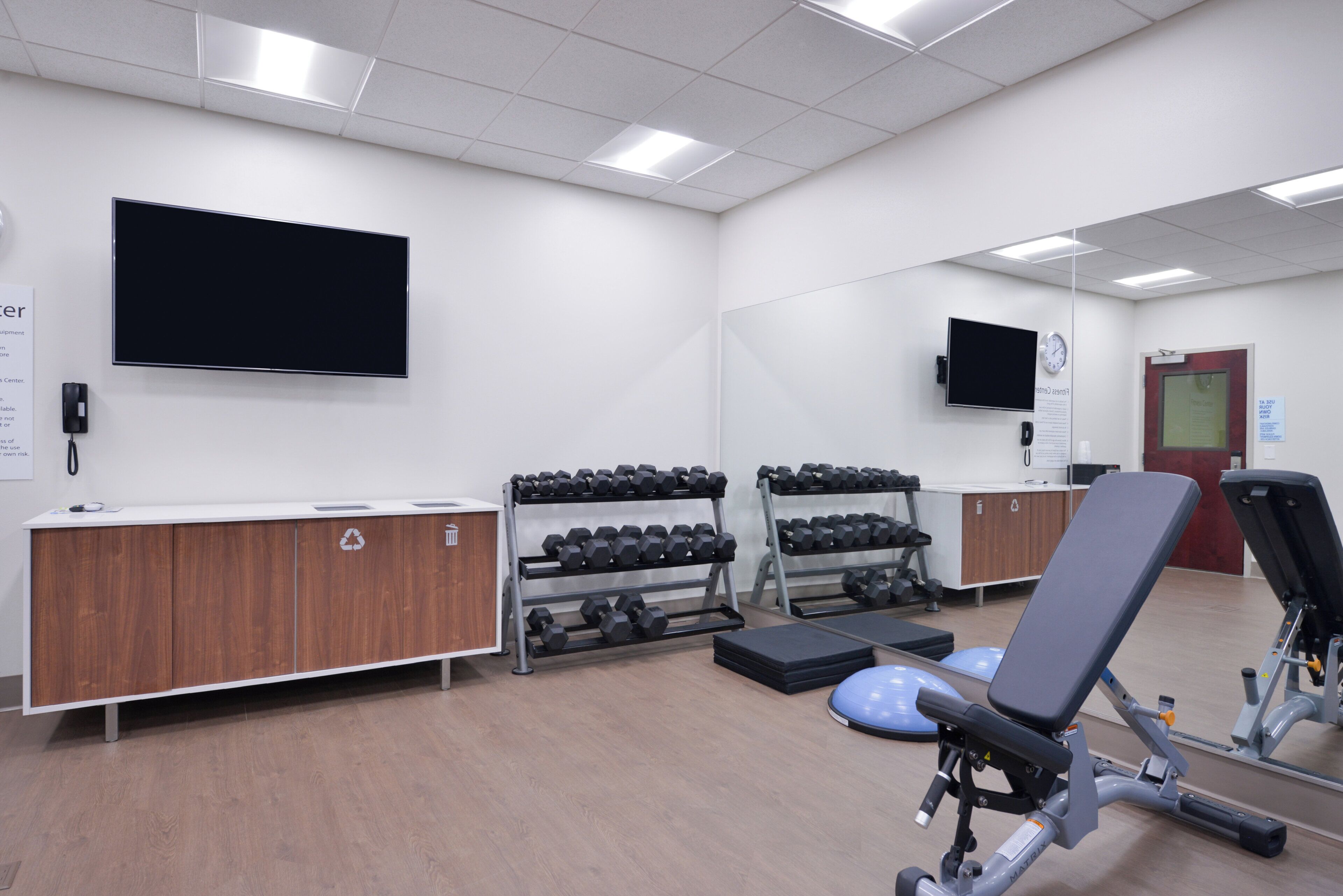 Un gimnasio con equipo de ejercicio, una televisión y una recepción.