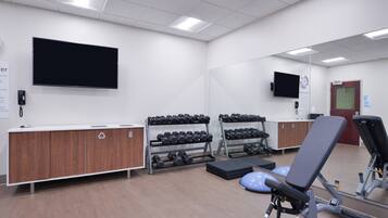 Un gimnasio con equipo de ejercicio, una televisión y una recepción.