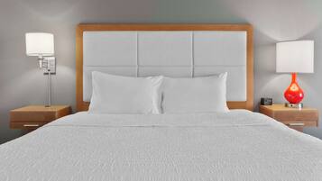 A neatly made bed with a wooden headboard, two bedside tables with lamps, and a wall clock.