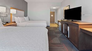 Una habitación de hotel con dos camas, una televisión de pantalla plana, un escritorio y una lámpara.