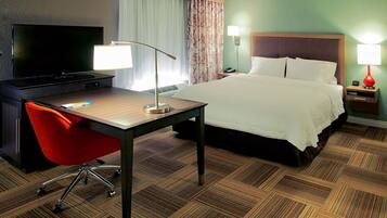 A hotel room with a bed, desk, chair, TV, and lamps.