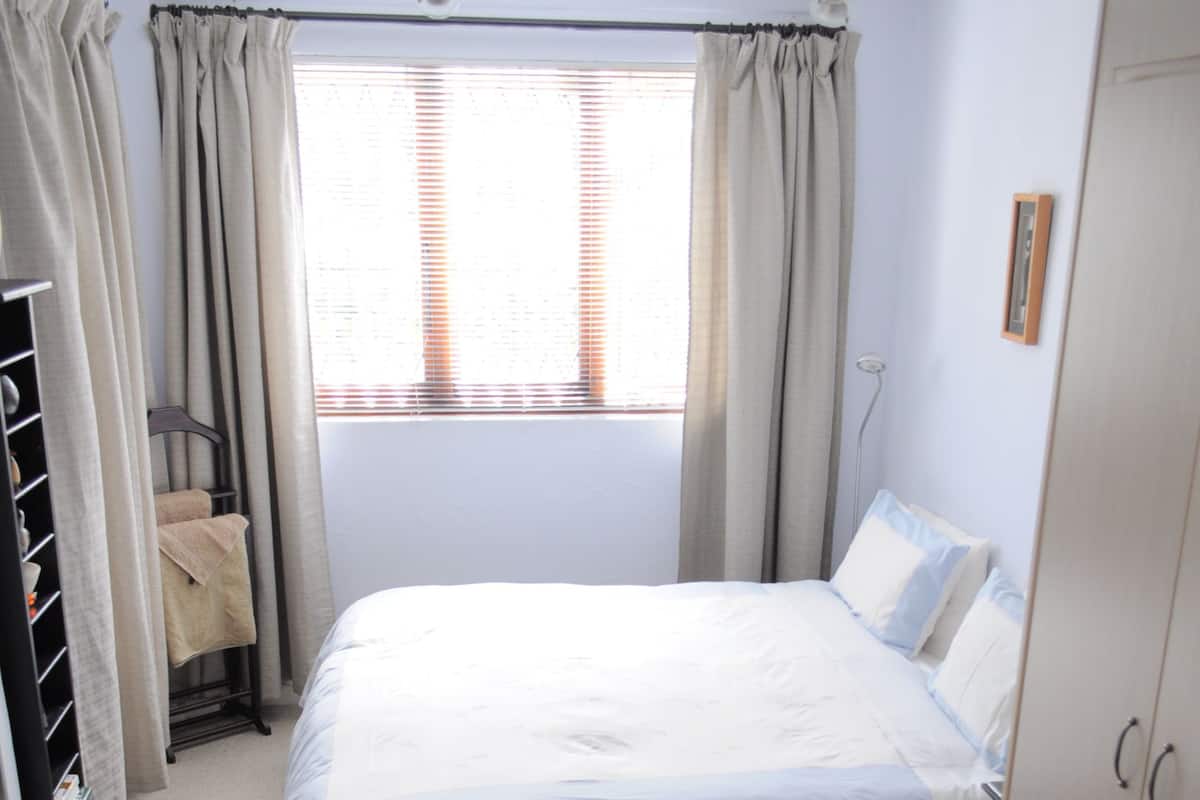 Una habitación de hotel ordenada con una cama, un escritorio y un armario.