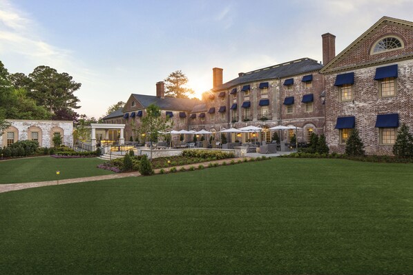 A large brick building with a courtyard, outdoor seating, and a well-maintained lawn. - Williamsburg Inn, an official Colonial Williamsburg Hotel (Williamsburg)