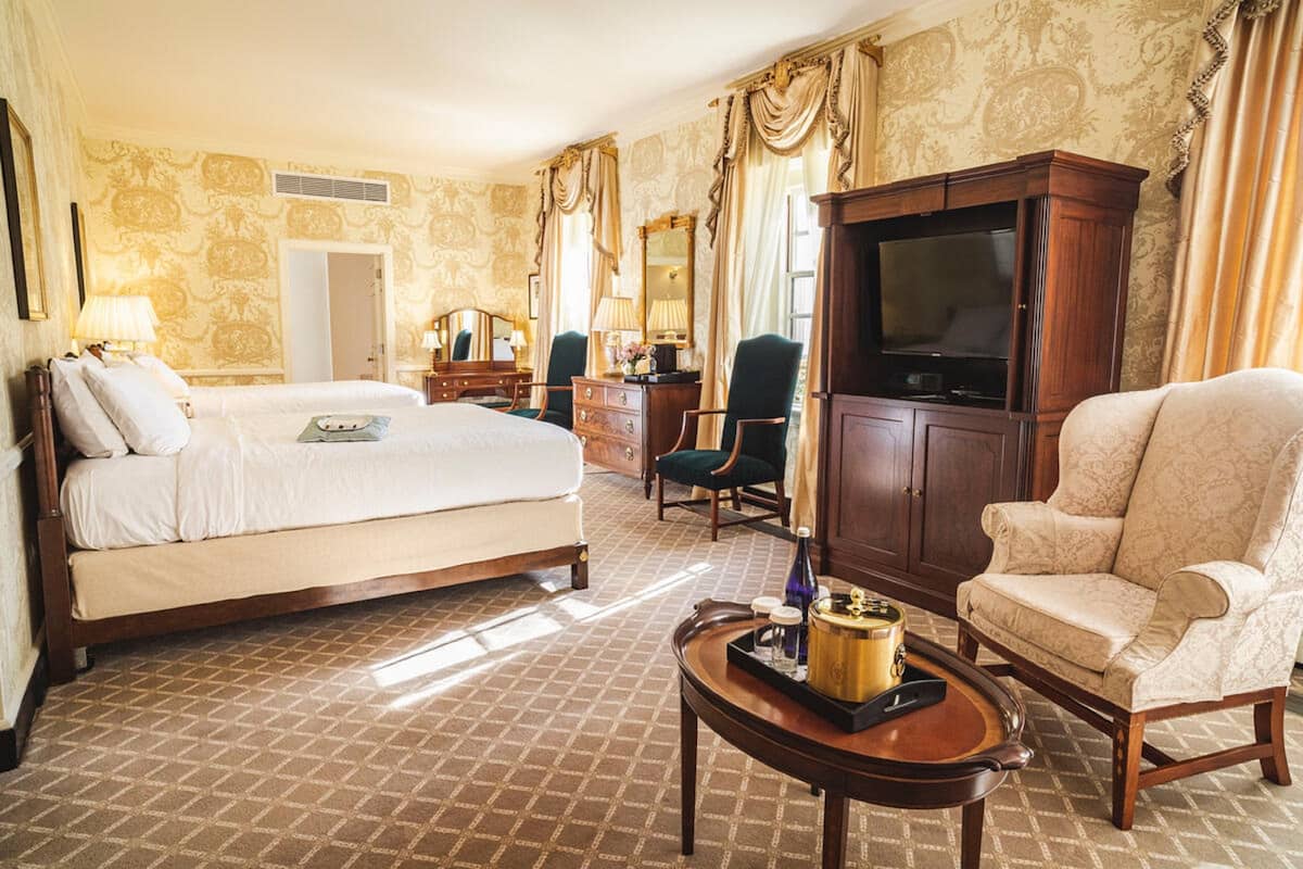 A hotel room with a bed, a TV, a desk, a chair, and a cabinet.