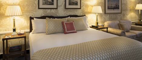 A hotel room with a large bed, two bedside tables with lamps, a sofa, and three framed pictures on the wall.