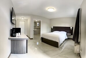 A modern hotel room with a bed, bedside table, and a built-in TV. - Hialeah Airport Motel (Hialeah)