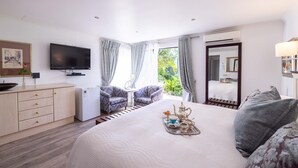 Ein Hotelzimmer mit Bett, Fernseher, Schreibtisch, Stuhl und einem Fenster mit Vorhängen.
