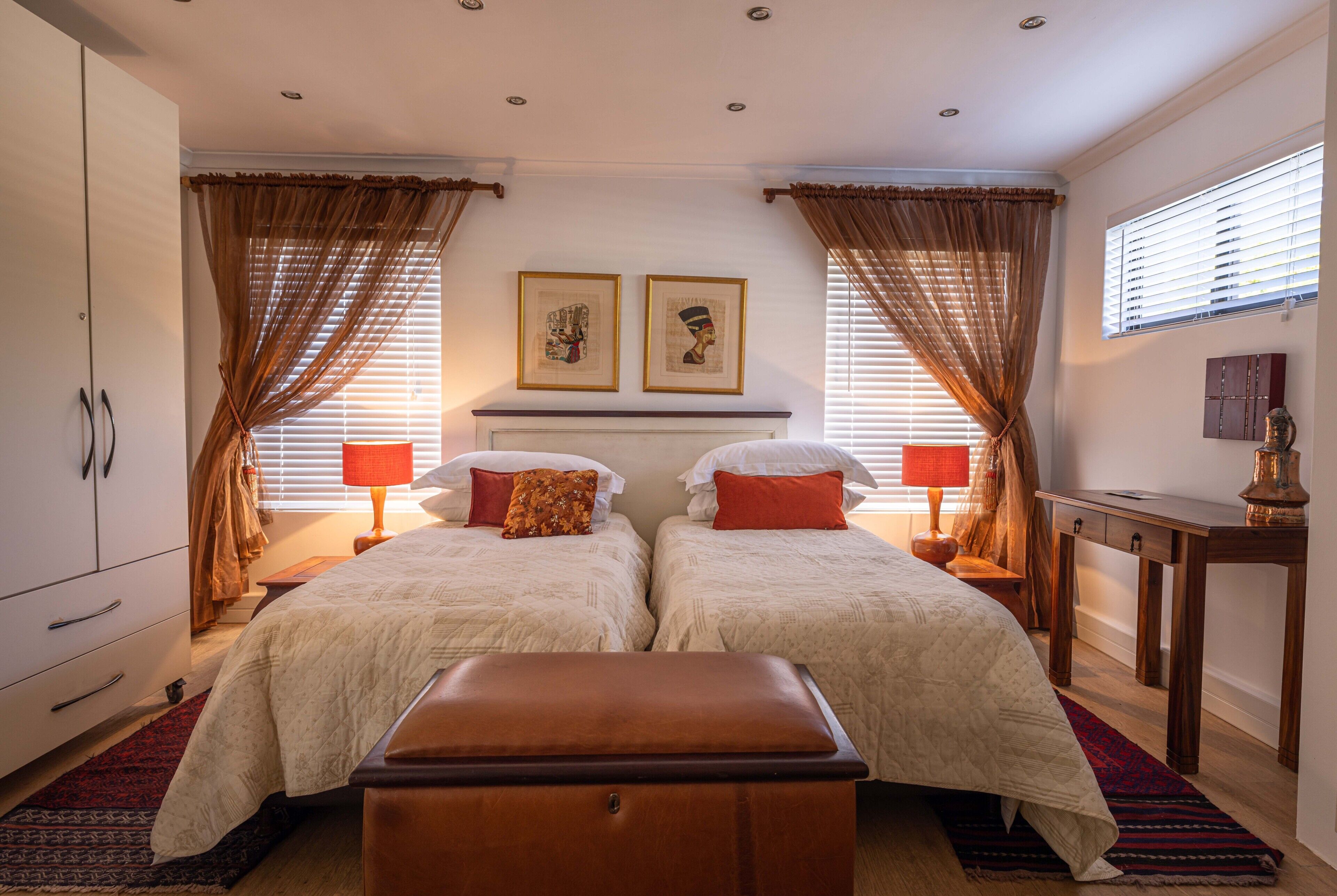 A double bedroom with two beds, a nightstand, a dresser, and a desk.