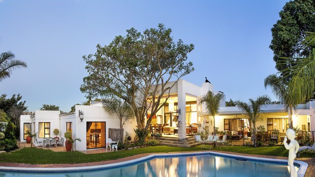 Ein modernes Haus mit Swimmingpool, Gartenmöbeln und einem gepflegten Garten.