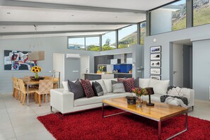 Ein modernes Wohnzimmer mit einem weißen Sofa, einem roten Teppich und einem Essbereich mit einem Holztisch und Stühlen.