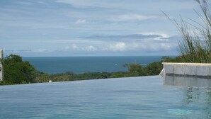 A clear blue infinity pool with a view of the ocean and distant land. - Eden Tica Lodge (Bahía Ballena)