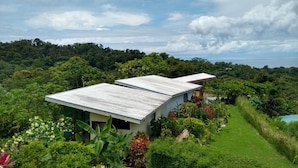 A modern two-story building with a flat roof, surrounded by lush greenery and a clear sky. - Eden Tica Lodge (Bahía Ballena)