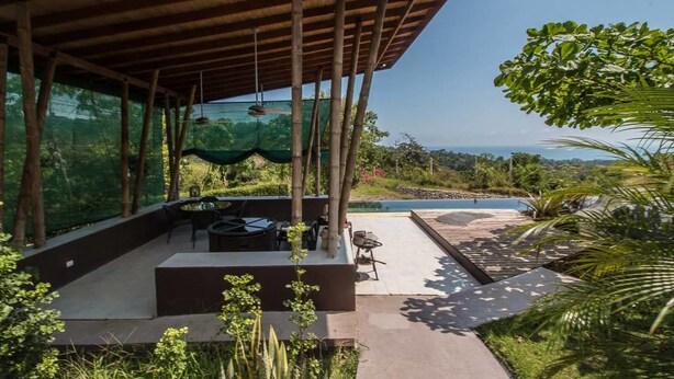 A covered outdoor area with a pool, seating, and lush greenery. - Eden Tica Lodge (Bahía Ballena)