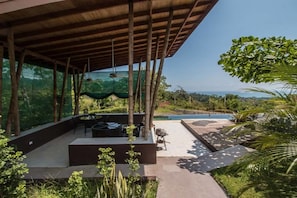 Un espacio al aire libre cubierto con piscina, mobiliario y abundante vegetación.