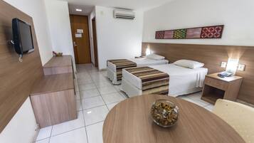 Une chambre d’hôtel comprenant un lit, des tables de chevet, une télévision et un coin repas avec une table et des chaises.