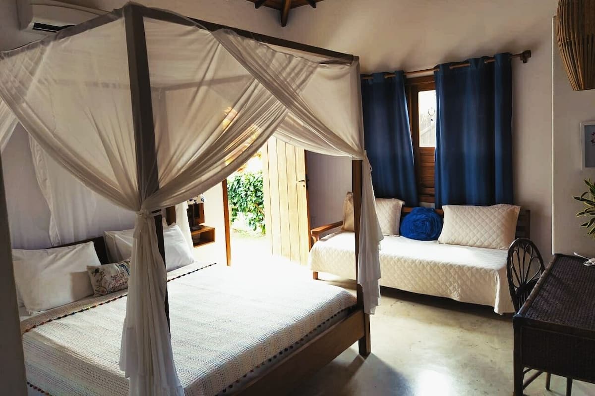 Ein Schlafzimmer mit Baldachinbett, Schlafsessel und kleinem Tisch.
