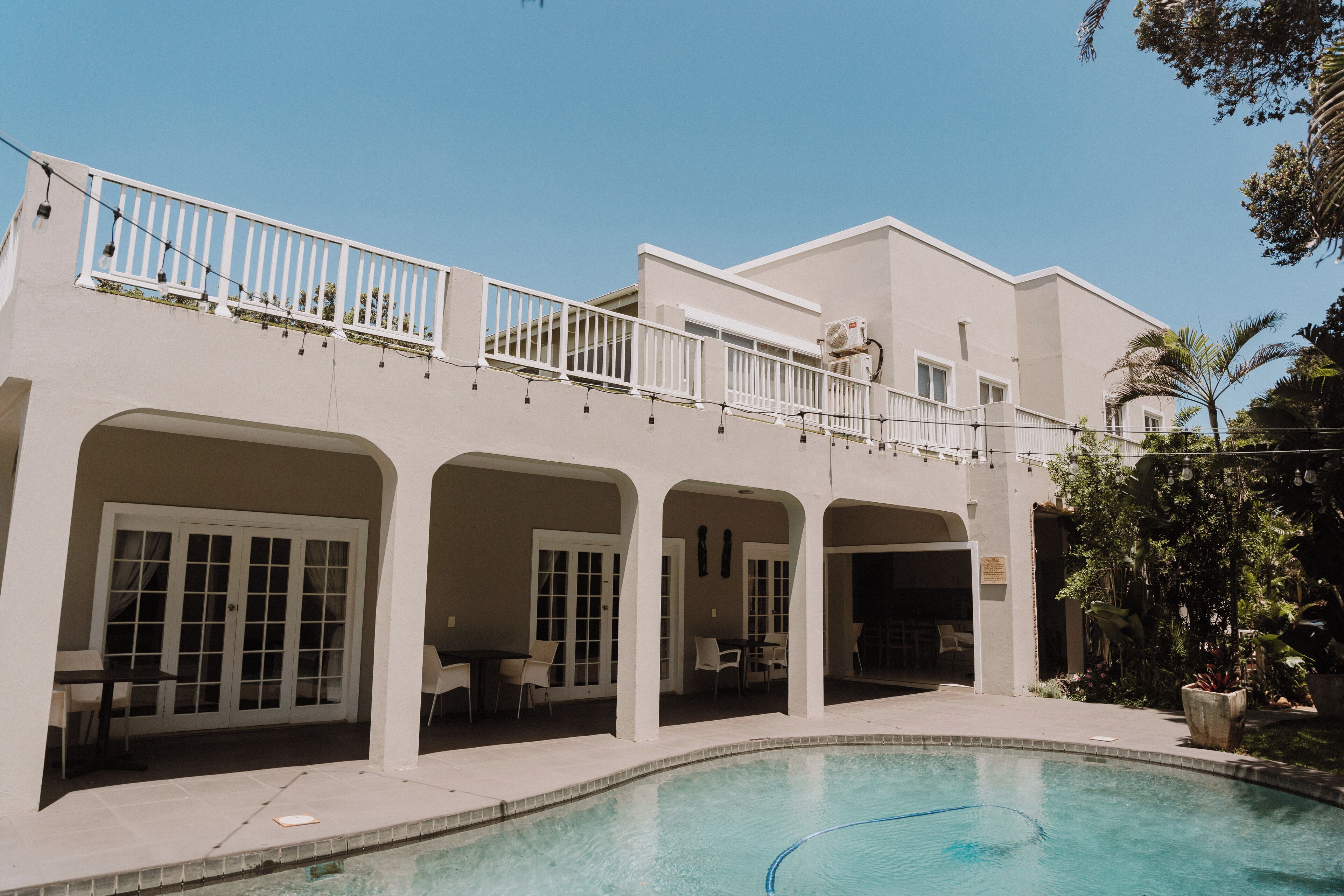 A modern building with a pool, covered patio, and outdoor seating areas.