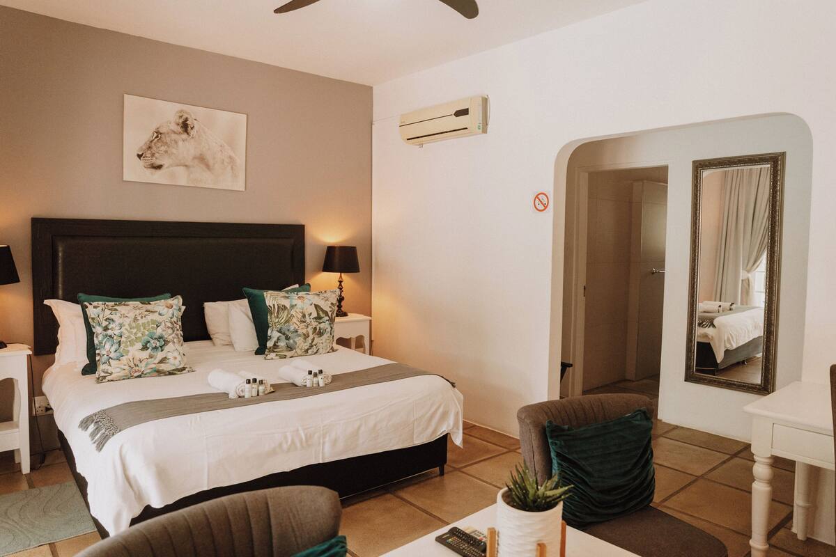 Une chambre d’hôtel comprenant un lit, des tables de chevet, un miroir et une porte donnant sur une salle de bain.