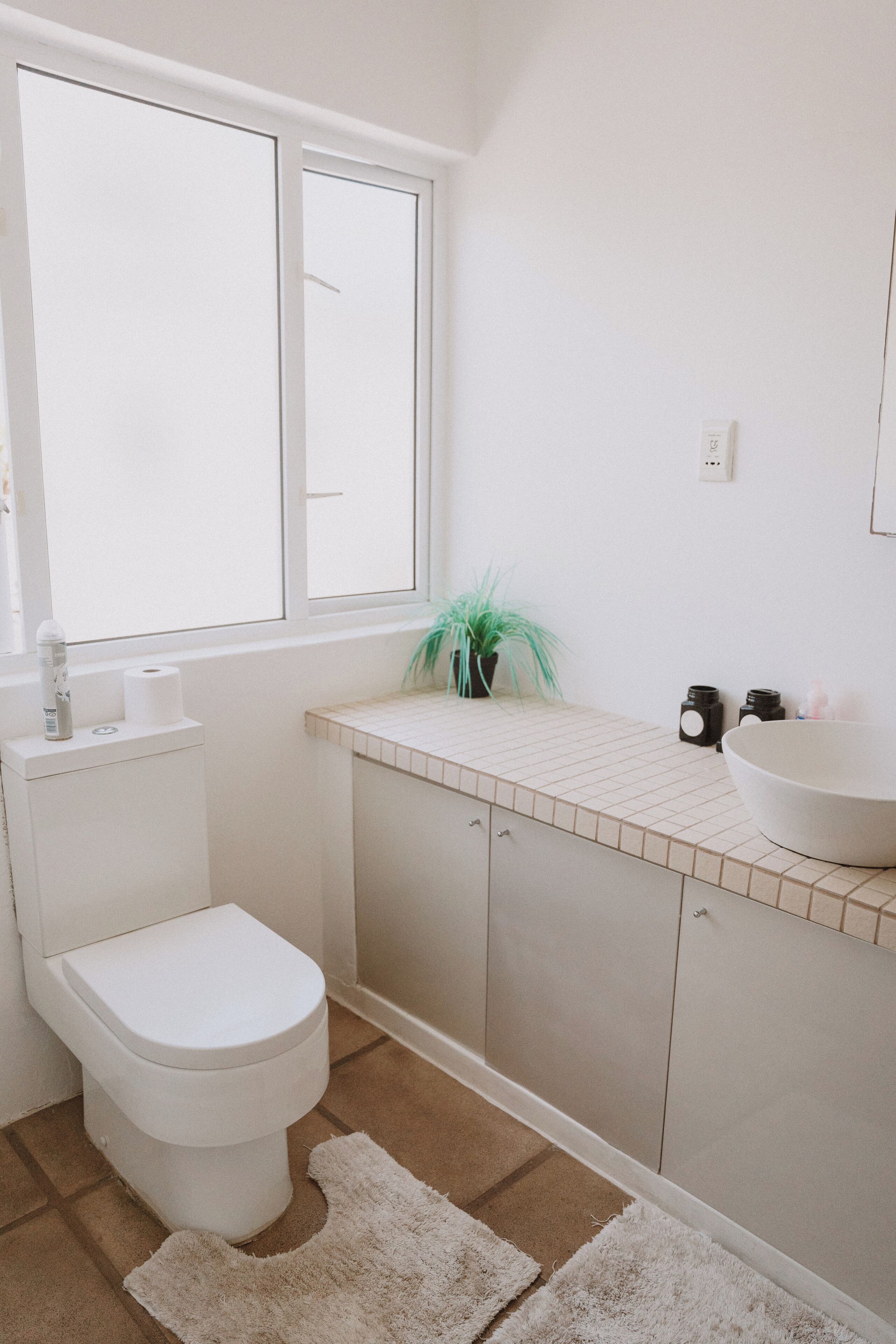 A bathroom with a toilet, sink, and window.
