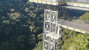 A high observation tower with a metal framework and a flat roof, overlooking a forested valley.