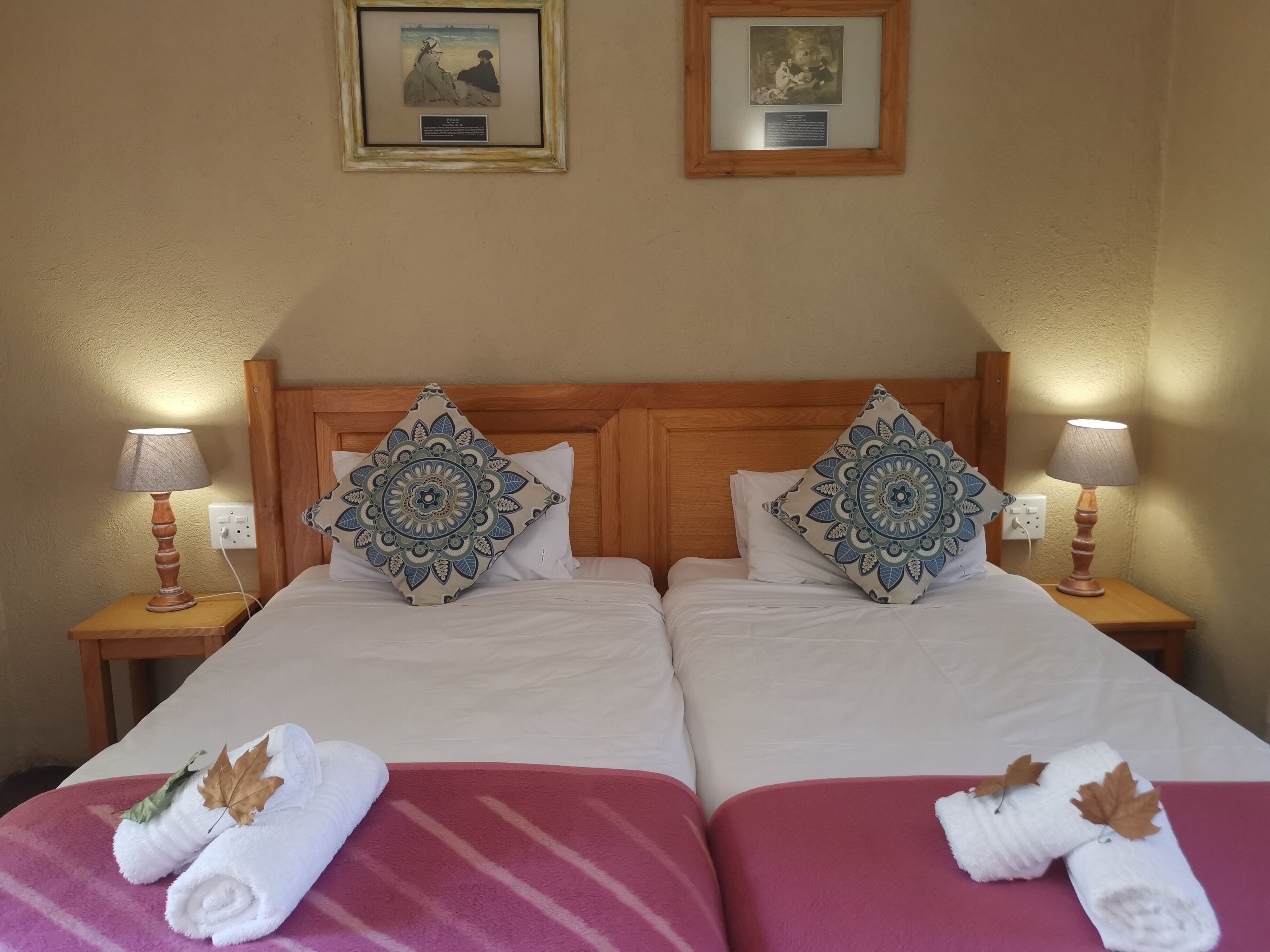 Uma cama de casal com duas almofadas, uma mesa de cabeceira com abajur e um quadro pendurado na parede.