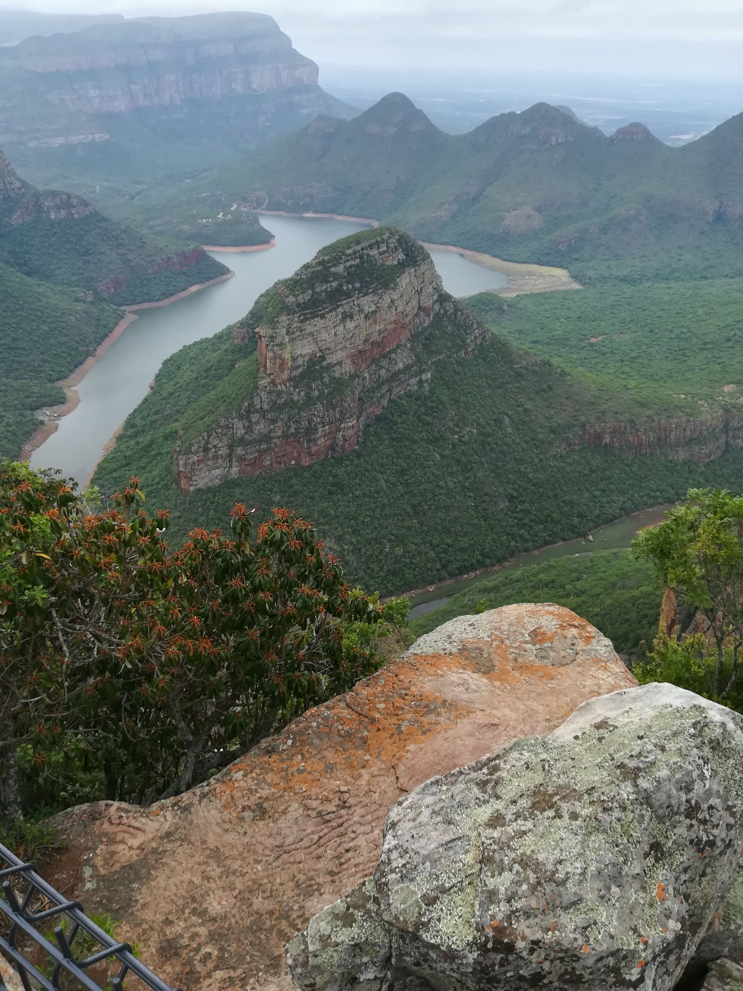 A mountainous landscape with a river, dense greenery, and rocky outcrops.