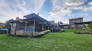 A two-story house with a covered porch, a stone foundation, and a well-maintained lawn. - Ash River Lodge B&B (Clarens)