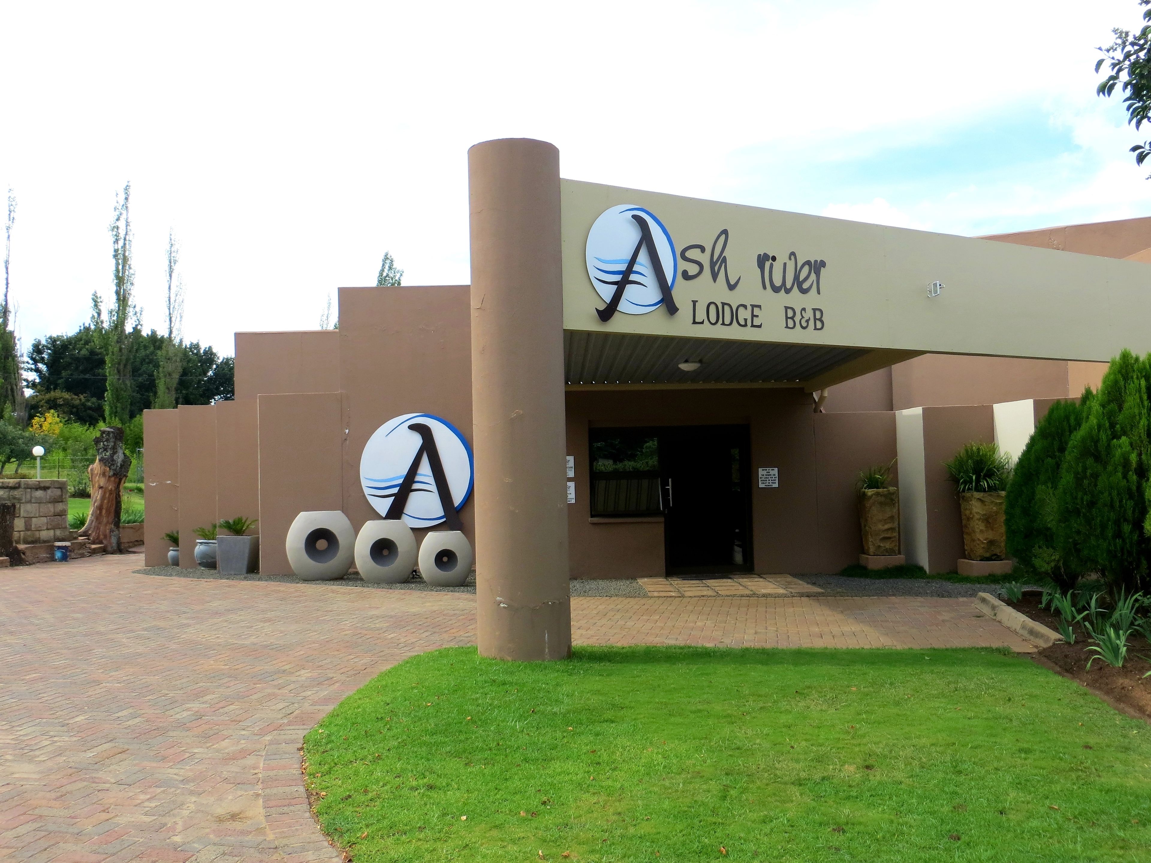 The Ash River Lodge B&B entrance with a prominent logo, a brick pathway, and a well-maintained lawn.