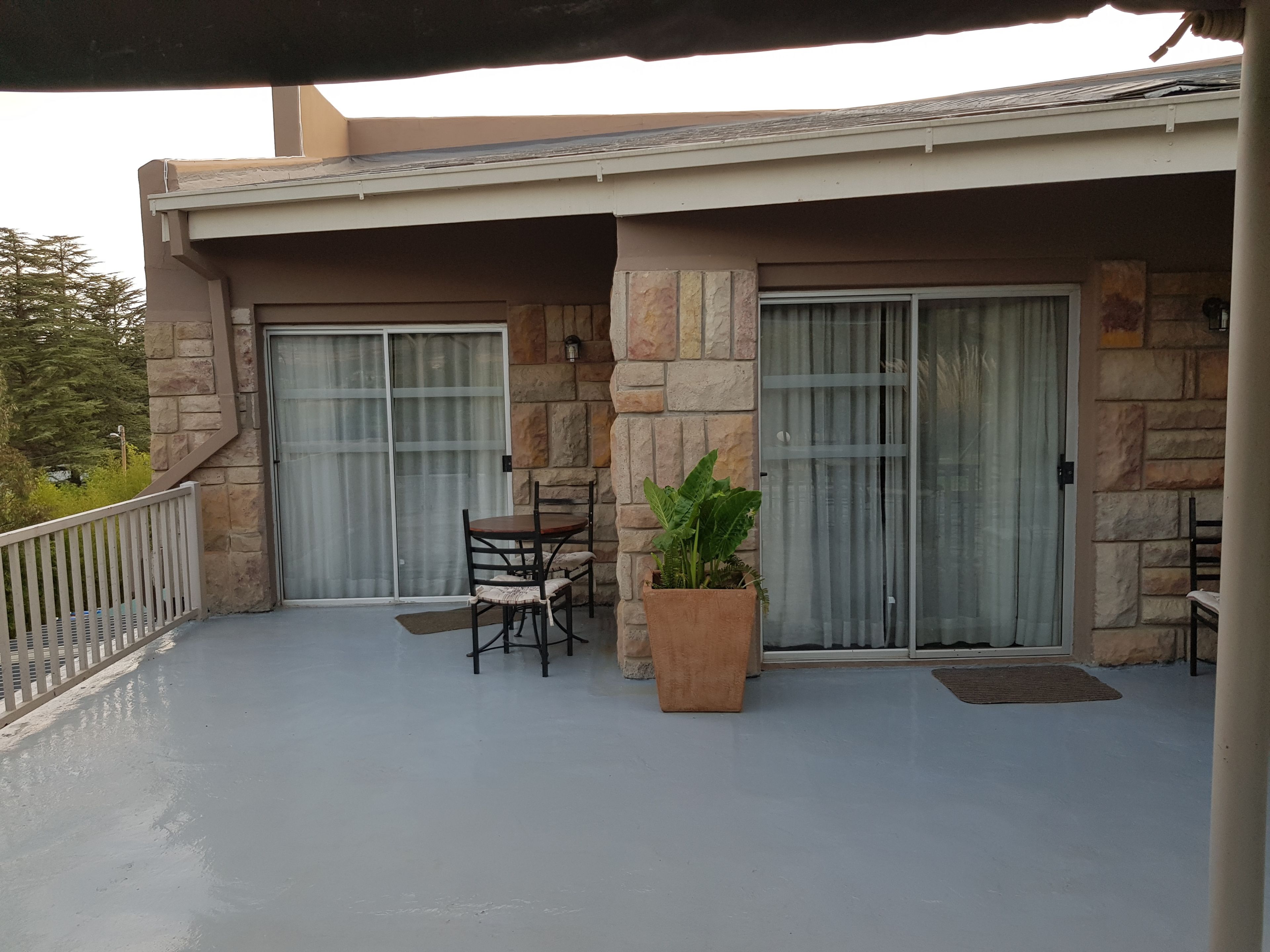 A covered outdoor area with a table and chairs, stone walls, and a potted plant.