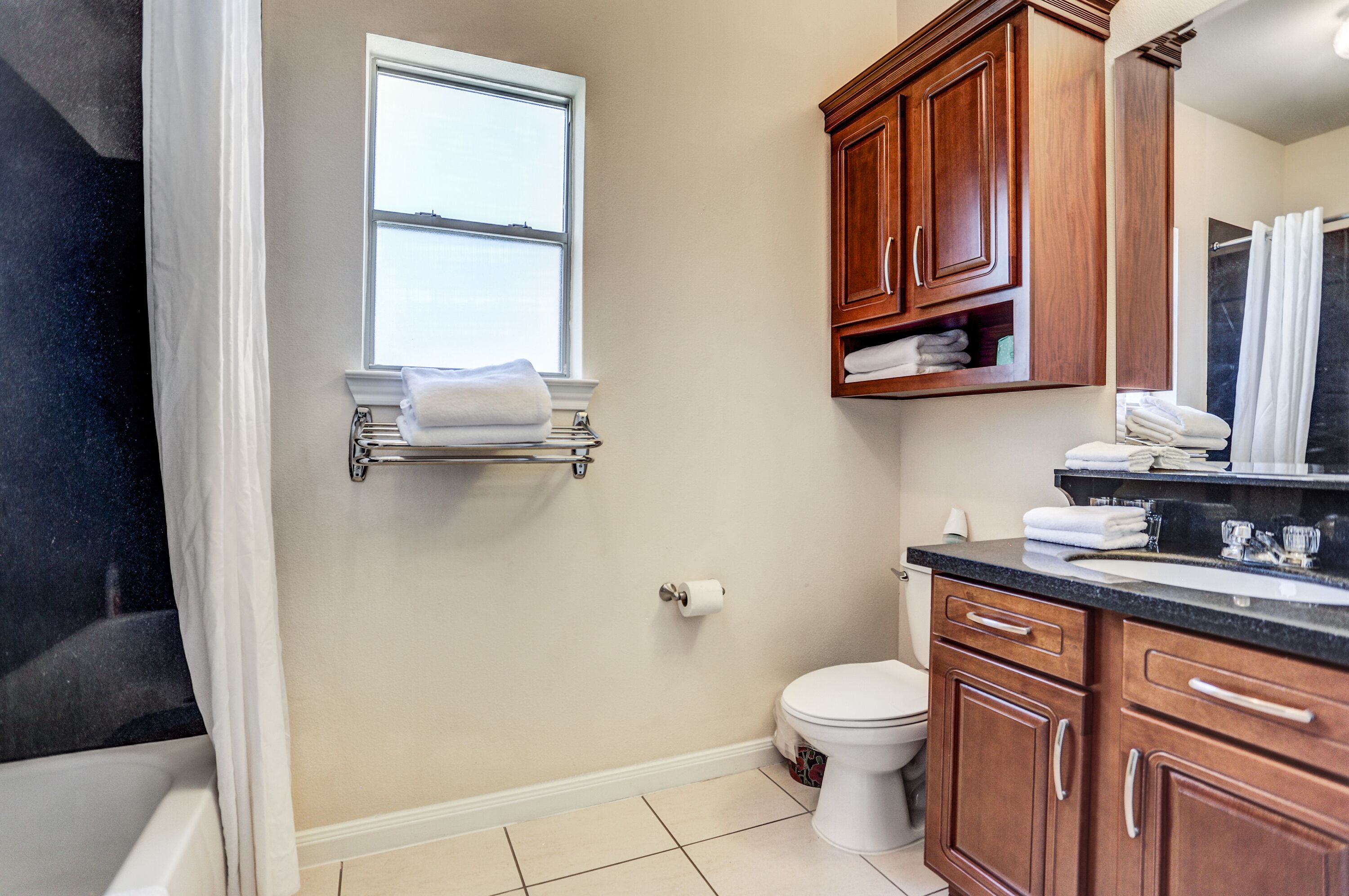 A bathroom with a toilet, sink, and wooden cabinets.