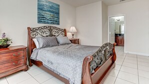 Une chambre à coucher comprenant un lit, une table de chevet, une commode et un ventilateur de plafond.