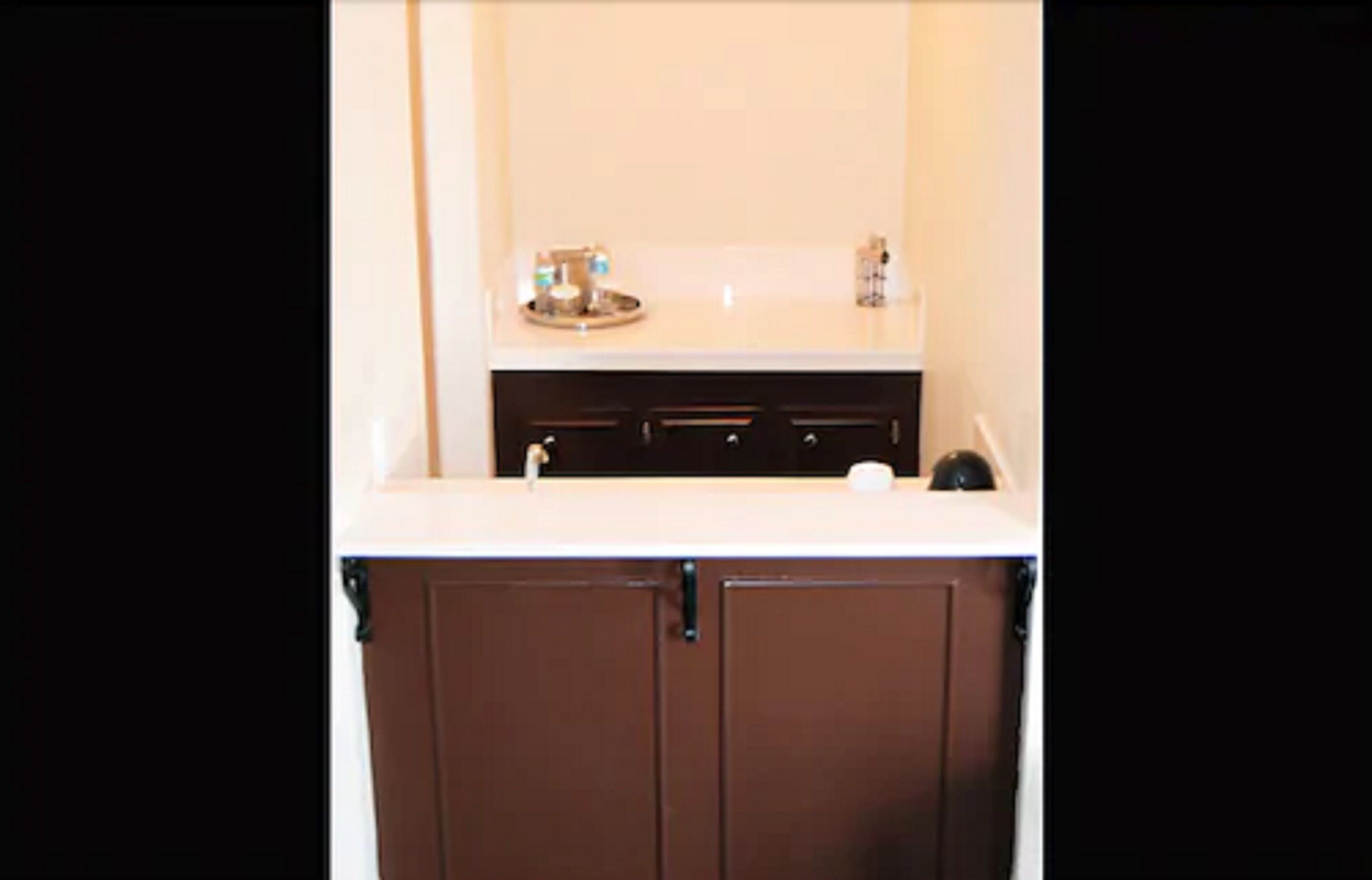 Un bagno con un lavabo bianco, un lavandino e uno specchio. Sono presenti articoli da toilette sul lavabo.