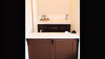 Un bagno con un lavabo bianco, un lavandino e uno specchio. Sono presenti articoli da toilette sul lavabo.