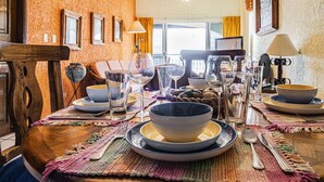 A dining table set with multiple bowls, glasses, and cutlery, surrounded by a wooden chair and a bench.