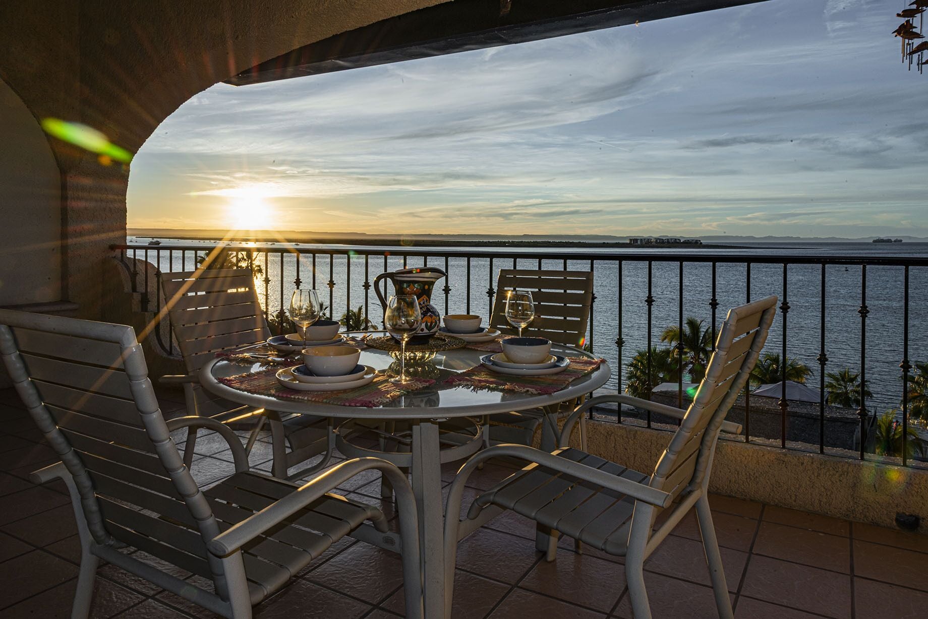 Une table dressée pour deux personnes, avec vue sur la mer et le coucher du soleil.