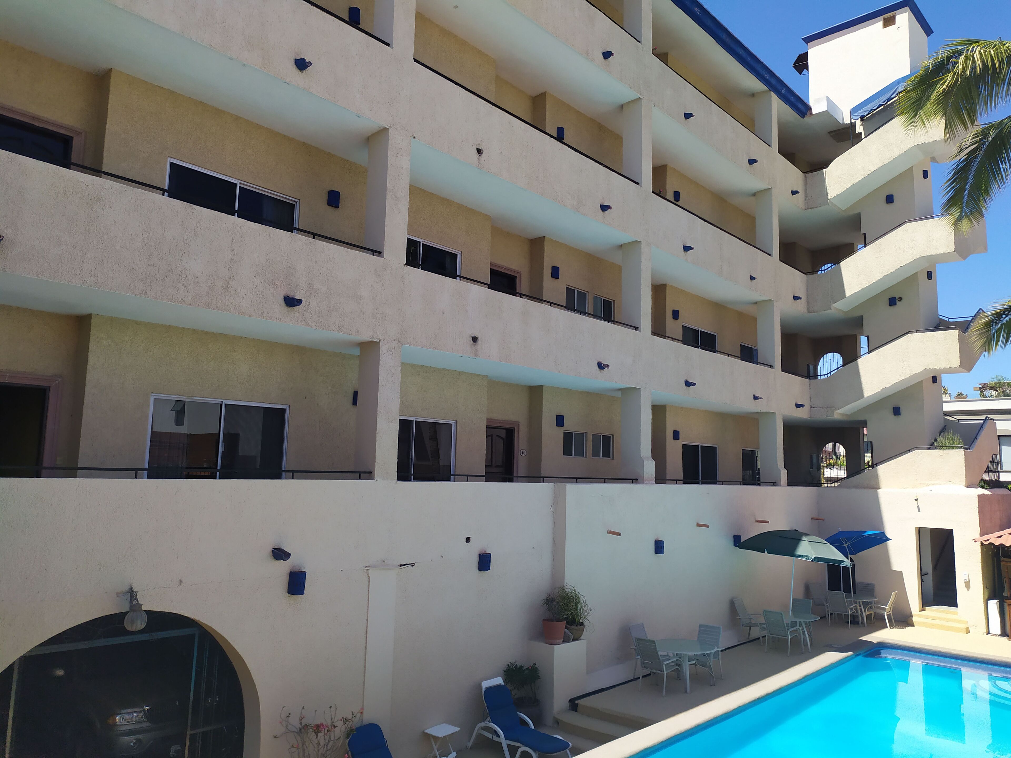 A multi-story hotel with balconies, a swimming pool, and outdoor seating.