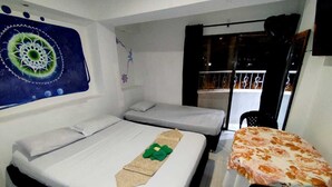 Camera d'albergo con due letti, un tavolino e un elemento decorativo al muro.