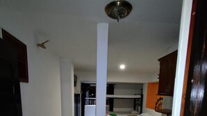 Un corridoio stretto che porta a una cucina con frigorifero, lavandino e pensili in legno.