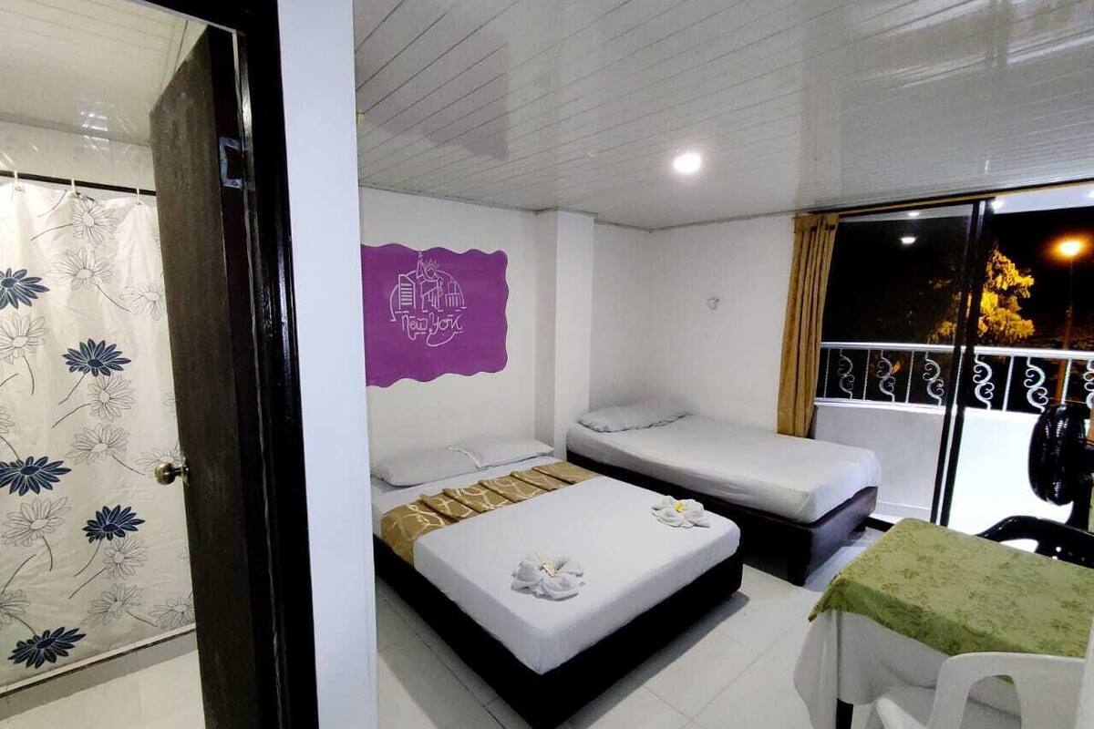 Une chambre avec deux lits, une petite table et un élément de décoration murale de couleur violette.