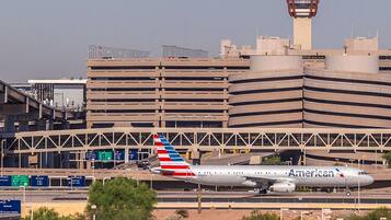 Um terminal de aeroporto com um grande avião da American Airlines estacionado, uma torre de controle e vários edifícios do terminal.