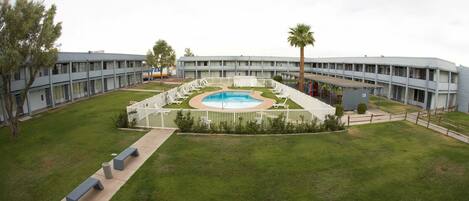 Un motel con piscina, varias habitaciones y un patio amurallado.