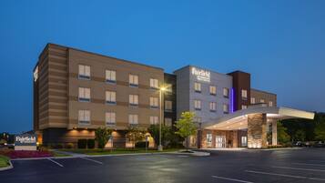 A multi-story hotel with a modern design, featuring a prominent entrance and a parking lot.