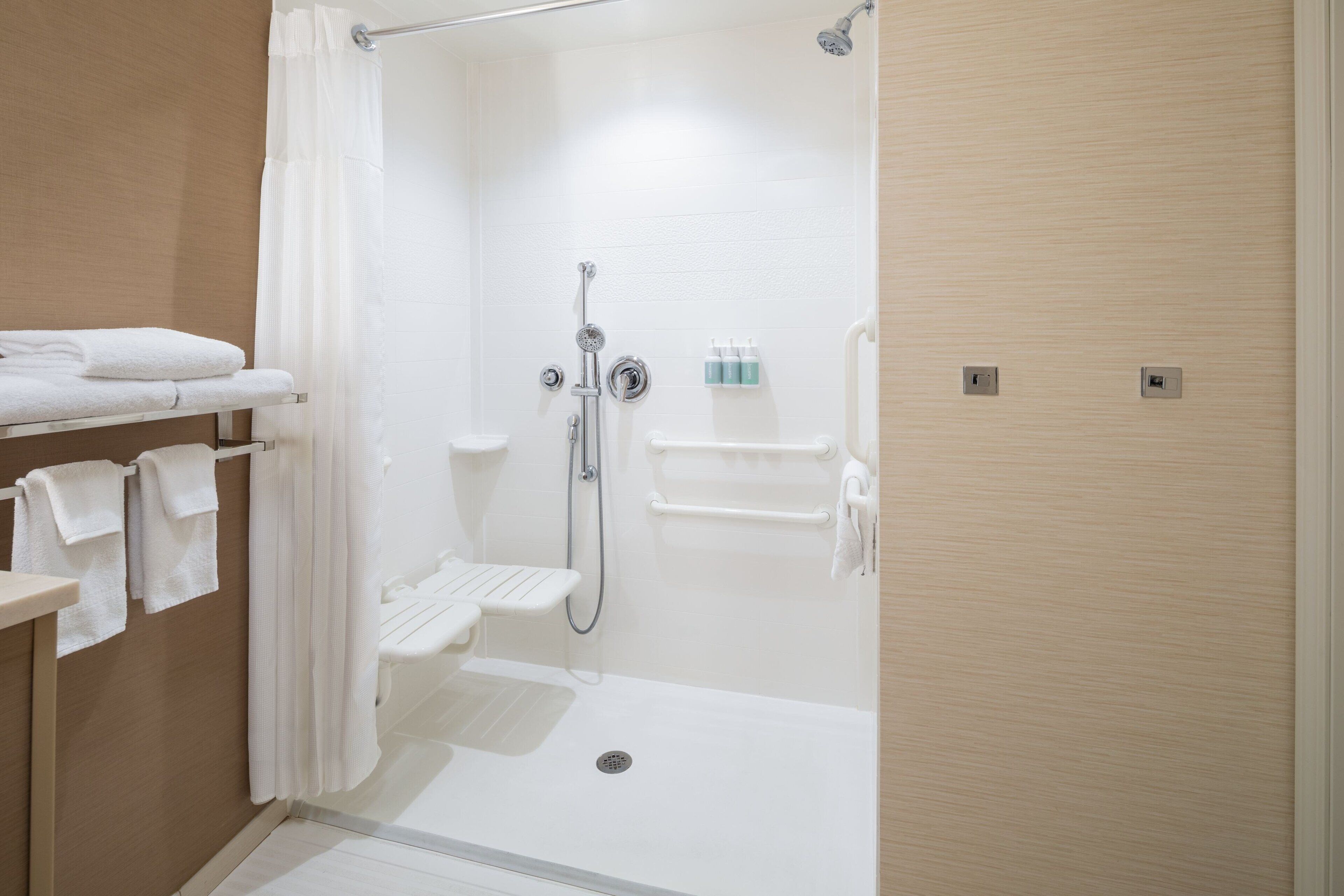 A modern bathroom with a shower, toilet, and towel rack.