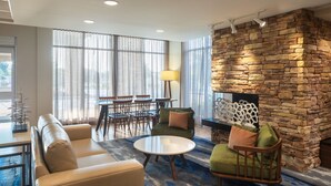 A modern living room with a stone fireplace, comfortable seating, and large windows. - Fairfield Inn and Suites by Marriott Chillicothe (Chillicothe)